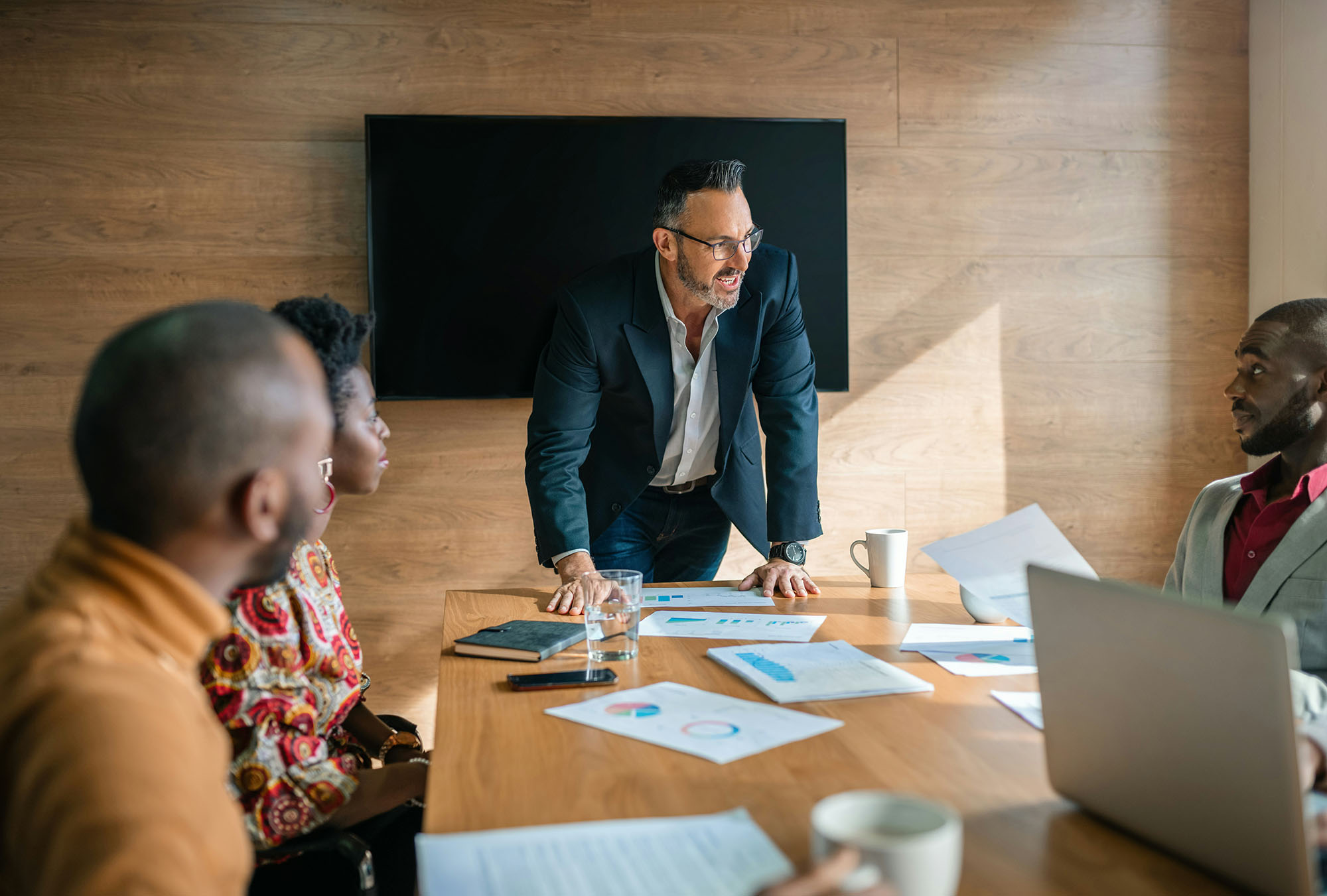 Leader weighing data and discussing a decision with a diverse team in a conference room