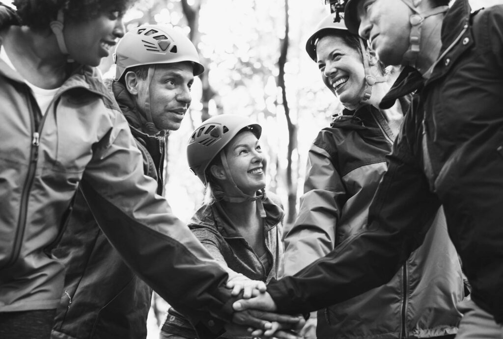Leadership cohort stacking hands together outdoors during a team-building activity