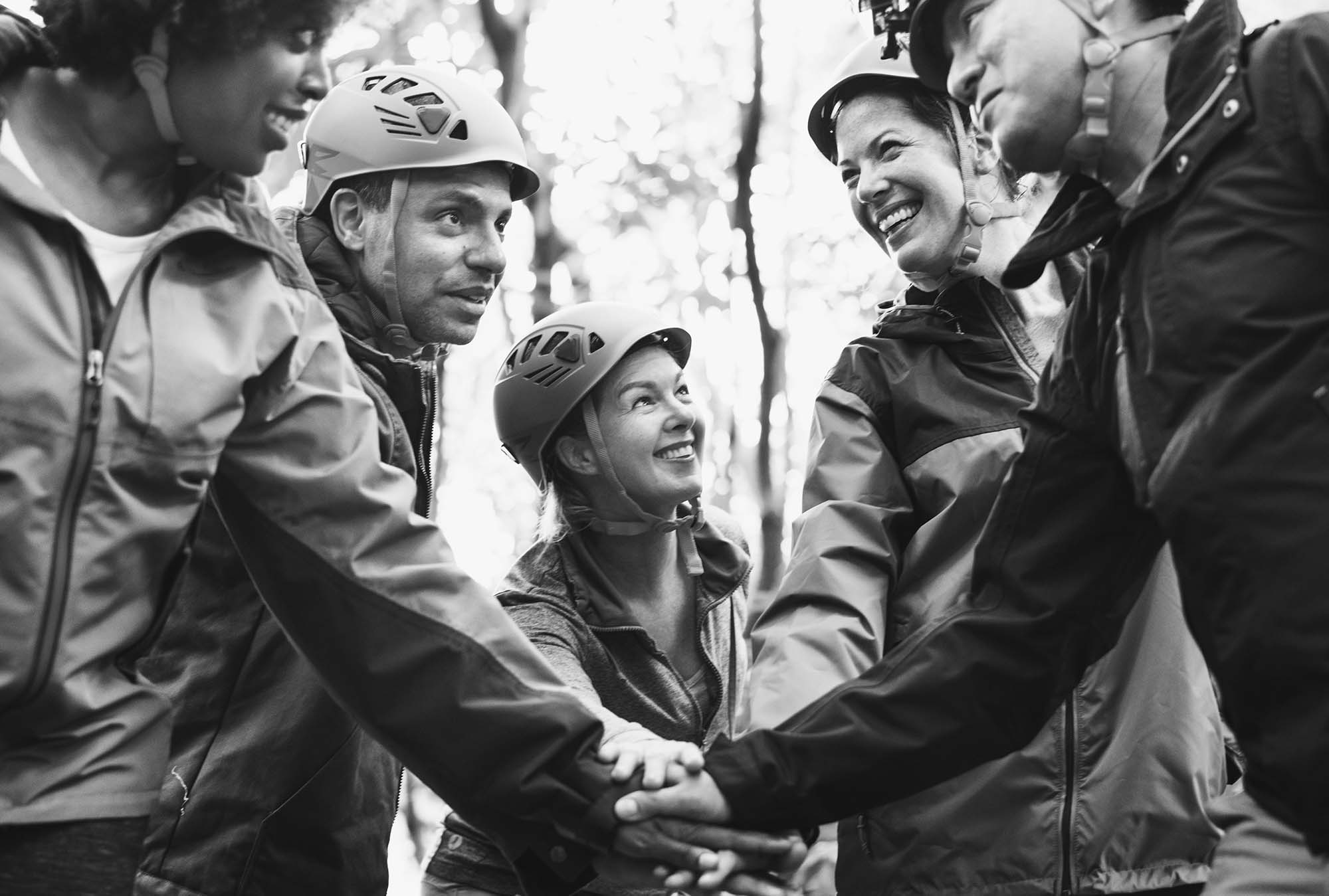 Leadership cohort stacking hands together outdoors during a team-building activity