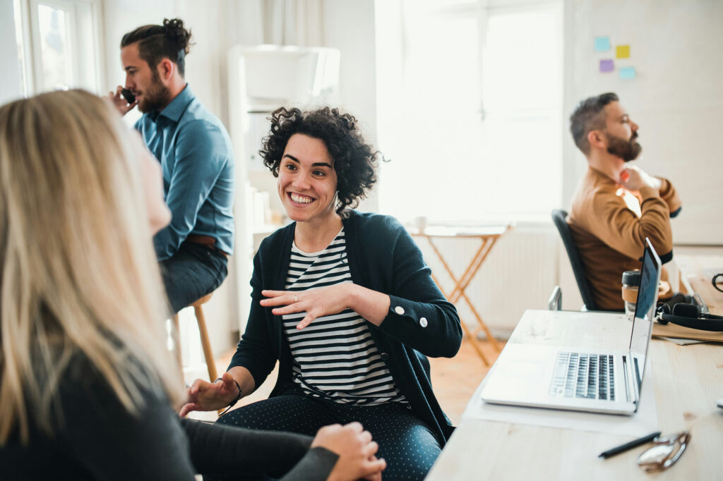 Two colleagues talking face to face in a bright open office